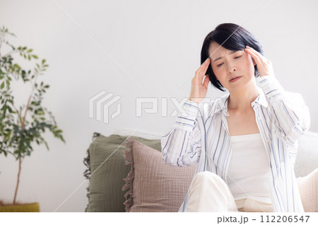 体調不良　頭痛で痛い頭をおさえるミドル女性 112206547