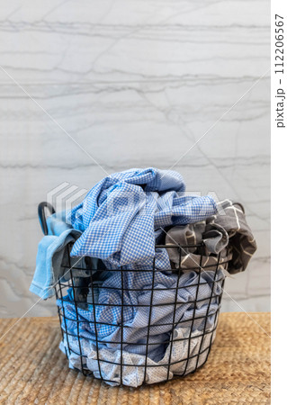 Metallic basket full of dirty clothes fabric on wicker carpet with washing machine dryer at bathroom 112206567