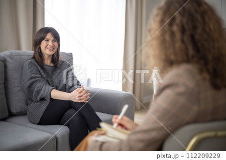 Woman psychologist talking to patient consulting at psychotherapy session making notes at office Woman psychologist talking to patient consulting at psychotherapy session making notes at office 112209229