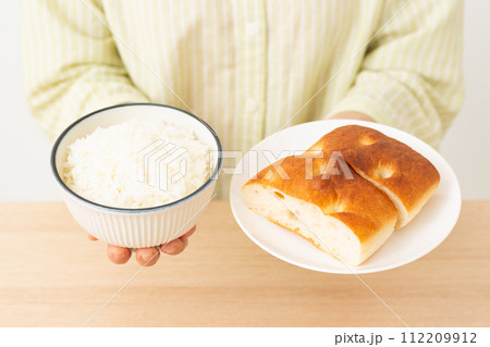 パンとご飯を持つ女性の手元 パンとご飯を持つ女性の手元 112209912