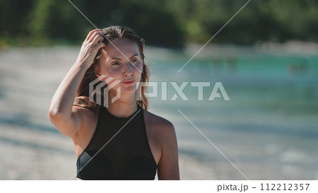 Beautiful young woman walk tropical beach. Caucasian girl in bikini enjoy nature landscape with blue sea and white sand shore. Relax on tropical island, nature summer scene. Travel, tourism, holiday 112212357