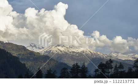 A vast landscape with clear skies, clouds, and snowy mountains. 112213771
