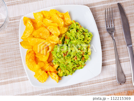 Beer snacks are laid out on plate - chips and portion of thick pasta sauce guacamole 112215369