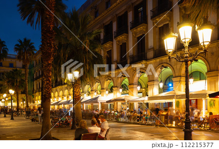 Evening view of bustling Placa Reial in Barcelona with cafes 112215377