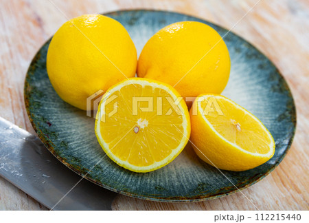 Ripe yellow whole lemons and fruit cut in half lie on wooden table 112215440