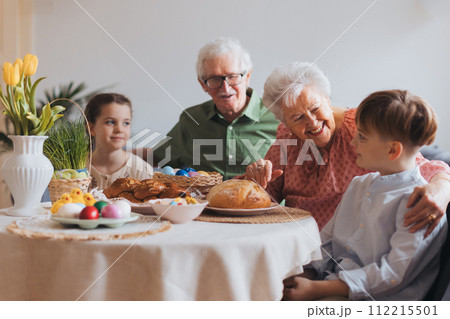 Grandparents with grandchildren eating traditional easter lunch. Recreating family traditions and customs. Happy easter. Grandparents with grandchildren eating traditional easter lunch. Recreating family traditions and customs. Happy easter. 112215501