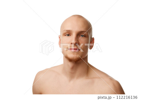 Portrait of handsome bald young guy in his 20s standing shirtless, looking at camera isolated against white studio background Portrait of handsome bald young guy in his 20s standing shirtless, looking at camera isolated against white studio background 112216136
