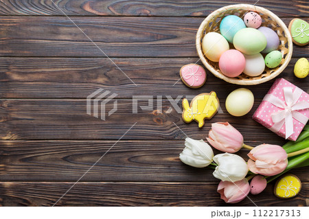 Easter frame with eggs, gift box and tulip on a colored background. The minimal concept. Top view Happy Easter composition. Card with a copy space of the place for the text 112217313