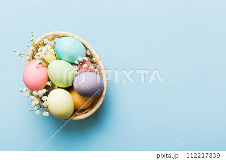 Happy Easter composition. Easter eggs in basket on colored table with gypsophila. Natural dyed colorful eggs background top view with copy space Happy Easter composition. Easter eggs in basket on colored table with gypsophila. Natural dyed colorful eggs background top view with copy space 112217839