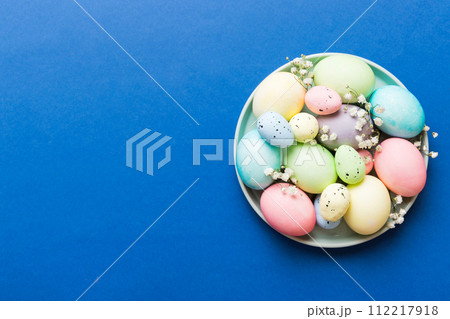Happy Easter composition. Easter eggs in basket on colored table with gypsophila. Natural dyed colorful eggs background top view with copy space Happy Easter composition. Easter eggs in basket on colored table with gypsophila. Natural dyed colorful eggs background top view with copy space 112217918