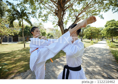 Young couple attending outdoor taekwondo fight training Young couple attending outdoor taekwondo fight training 112218462