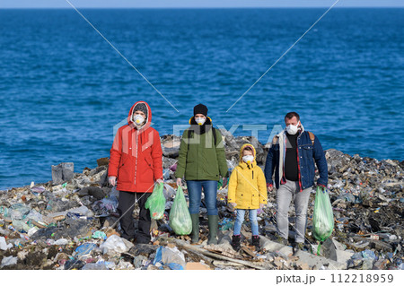 Little girl among eco activists standing on coastline, shore of sea. Environmental pollution, eco activism and plogging concept. 112218959