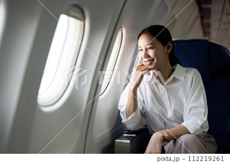 Successful asian businesswoman or female entrepreneur in a plane sits in a business class seat Successful asian businesswoman or female entrepreneur in a plane sits in a business class seat 112219261