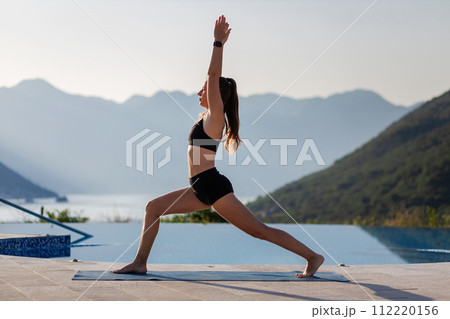 Outdoor yoga practicing at mountain resort near the pool. Outdoor yoga practicing at mountain resort near the pool. 112220156