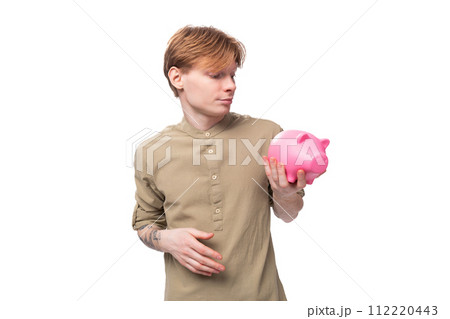 young handsome redhead student man holding piggy bank with savings 112220443