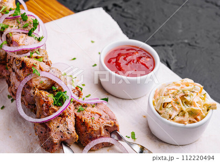 Juicy kebabs from pork on skewers laid out on a decorative board 112220494