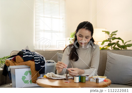 Woman repairs sews reuses fabric from old clothes economical reuse. DIY Hobby Reuse Recycling at home Woman repairs sews reuses fabric from old clothes economical reuse. DIY Hobby Reuse Recycling at home 112222081