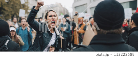Woman passionately yelling during protest, surrounded by crowd of demonstrators on city streets, expressing strong emotions 112222589