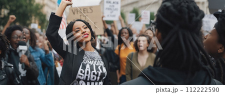 Woman african american up Fist Amidst Crowd at Protest, Expressing Outrage and Determination, Surrounded by Fellow Protesters Holding Signs 112222590