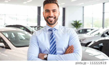 Auto sales manager exudes confidence, arms crossed, amidst range of luxury vehicles in well-lit modern car showroom, epitomizing professional success 112222619