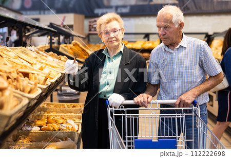 Mature european couple shopping buns and bread in bakery section of supermarket Mature european couple shopping buns and bread in bakery section of supermarket 112222698