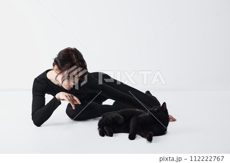 Bond between human and pet. Beautiful young woman in black clothes playing with black cat against white studio background Bond between human and pet. Beautiful young woman in black clothes playing with black cat against white studio background 112222767