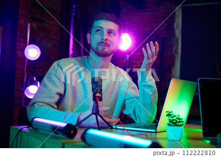 Young man, blogger taking part in online podcast show, giving interview, discussing interesting lifestyle topics Young man, blogger taking part in online podcast show, giving interview, discussing interesting lifestyle topics 112222810