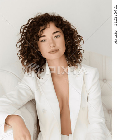 Confident Young Woman in Bright colored Blazer Sitting on a Bright colored Sofa 112225421