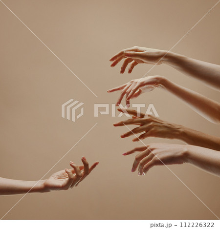 One hand reaching to other hands symbolizing support, community against sandy color studio background. One hand reaching to other hands symbolizing support, community against sandy color studio background. 112226322