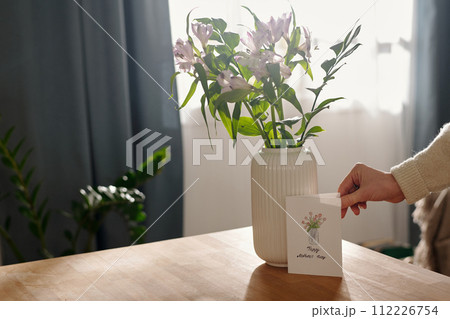 Putting postcard by vase with flowers 112226754