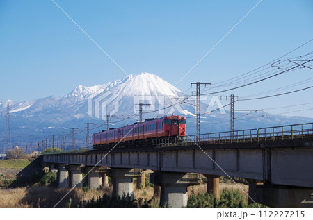 冠雪の大山を背景に日野川の鉄道橋梁を通過するキハ40系キハ47形普通列車（4両編成）の後ろ姿 112227215