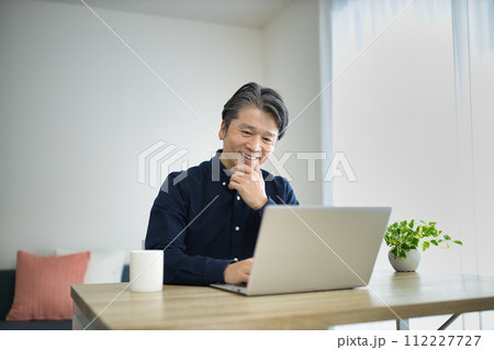 リビングでテレワークをするミドル男性 リビングでテレワークをするミドル男性 112227727