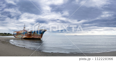 Rusted Shipwreck on Serene Beach Under Cloudy Sky 112228366