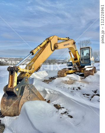 雪の中に停車する大きな黄色いショベルカー 112228961
