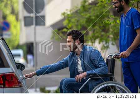 Man on a wheelchair getting into a car 112229251