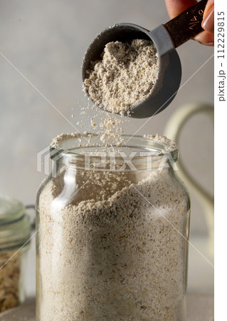 Oat flour pouring in a glass jar. Gluten free flour, oats, home baking. Oat flour pouring in a glass jar. Gluten free flour, oats, home baking. 112229815