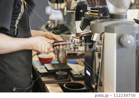 Expert Barista Crafting Espresso Excellence in Coffee Shop, grinding freshly roasted coffee in espresso machine 112230750