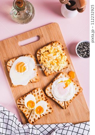 Eggs prepared to different recipes on toast on a wooden board top and vertical view 112232925