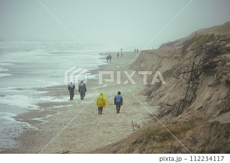 People walk on the beach in stormy weather in Sondervig Denmark People walk on the beach in stormy weather in Sondervig Denmark 112234117