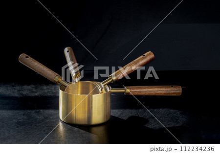 Set of Brass Measuring Cups with Wood Handles with Hanging Hole Design on dark background. Set of Brass Measuring Cups with Wood Handles with Hanging Hole Design on dark background. 112234236