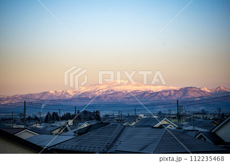 朝焼けに染まる雪の積もった月山 112235468
