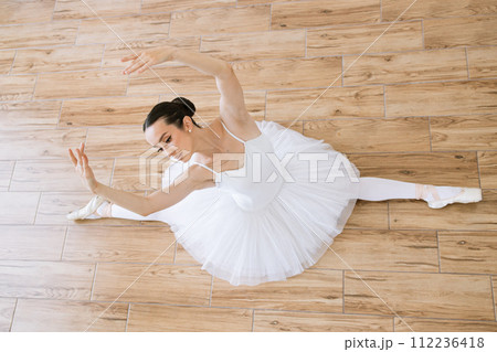 Top view of professional caucasian ballerina in white tutu and pointe stretching 112236418