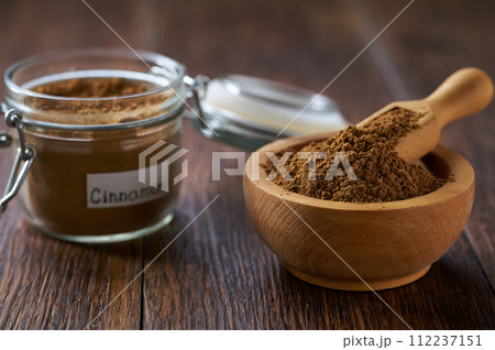 cinnamon powder in a wooden bowl on a dark wooden table, copy space for text. cinnamon powder in a wooden bowl on a dark wooden table, copy space for text. 112237151