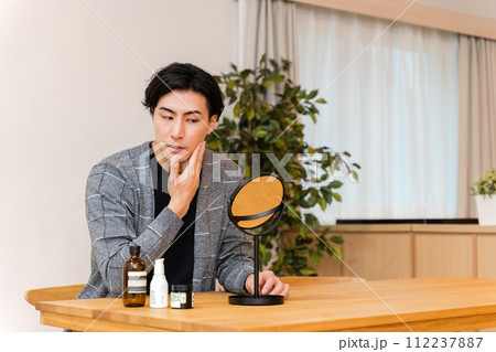 自宅リビングでメンズコスメを使用して肌のケアをする30代の男性(メンズビューティー) 自宅リビングでメンズコスメを使用して肌のケアをする30代の男性(メンズビューティー) 112237887