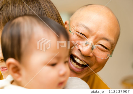 笑顔で0歳の赤ちゃんをあやすシニアのおじいちゃん 112237907