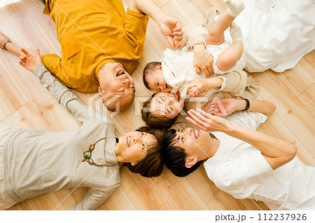 多人数で床に寝転がる3世帯の幸せな家族の笑顔 多人数で床に寝転がる3世帯の幸せな家族の笑顔 112237926