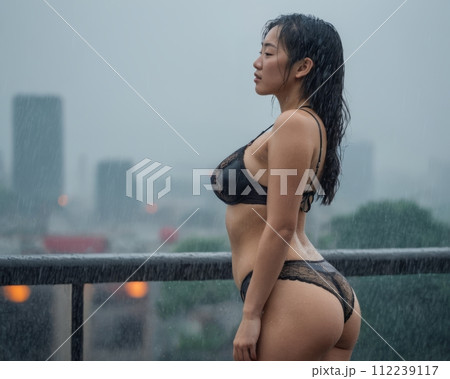 an asian woman in lingerie standing on a balcony in the rain 112239117