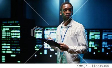 Computer scientist checking server racks performing data backups and providing centralized storage. Technician reviewing Uninterruptible Power Supply ensuring operational continuity Computer scientist checking server racks performing data backups and providing centralized storage. Technician reviewing Uninterruptible Power Supply ensuring operational continuity 112239300