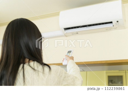 エアコンを操作する女性（リモコンにピント） 112239861