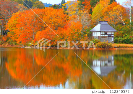 紅葉を映す湖面の小屋 112240572